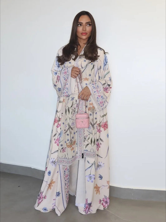 Woman wearing a floral dress holding a pink handbag against a white background
