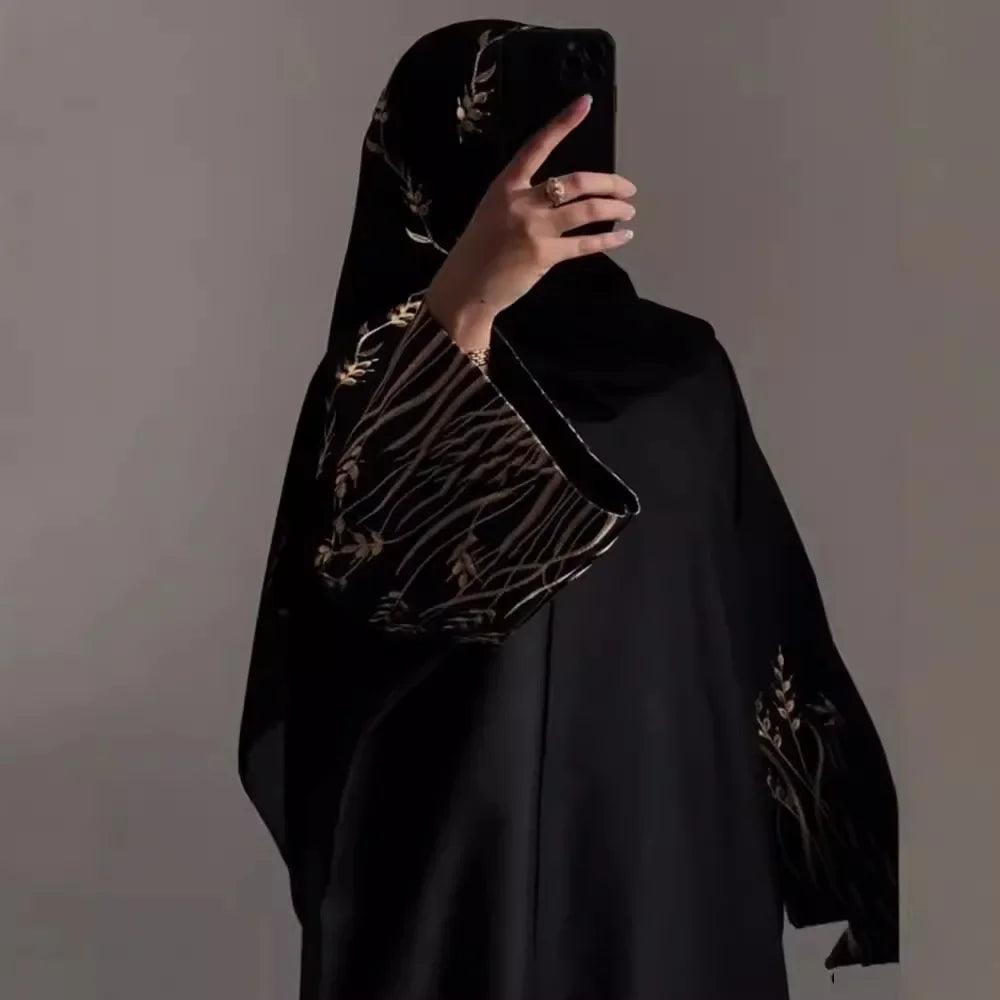 Black abaya with gold embroidery on a plain background