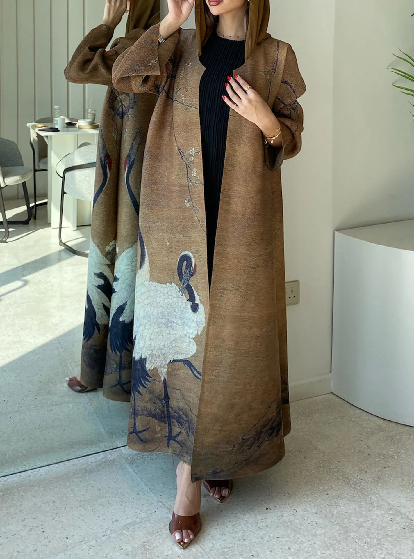 Person wearing a long brown coat with a floral pattern in an indoor setting.