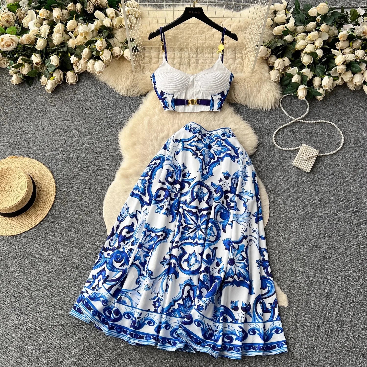 Blue and white patterned dress with a hat and flowers on a gray surface