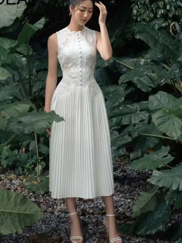 Woman in a white dress standing among green foliage