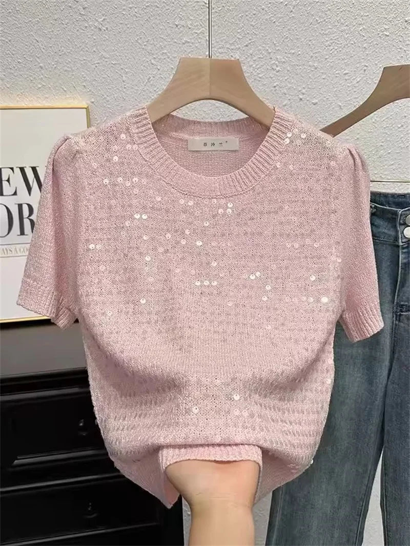 Pink sequin sweater on a hanger against a neutral background