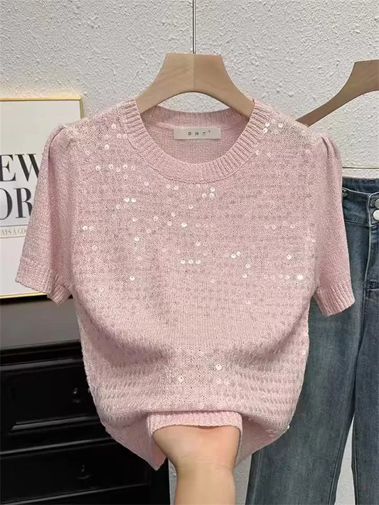 Pink sequin sweater on a hanger against a neutral background