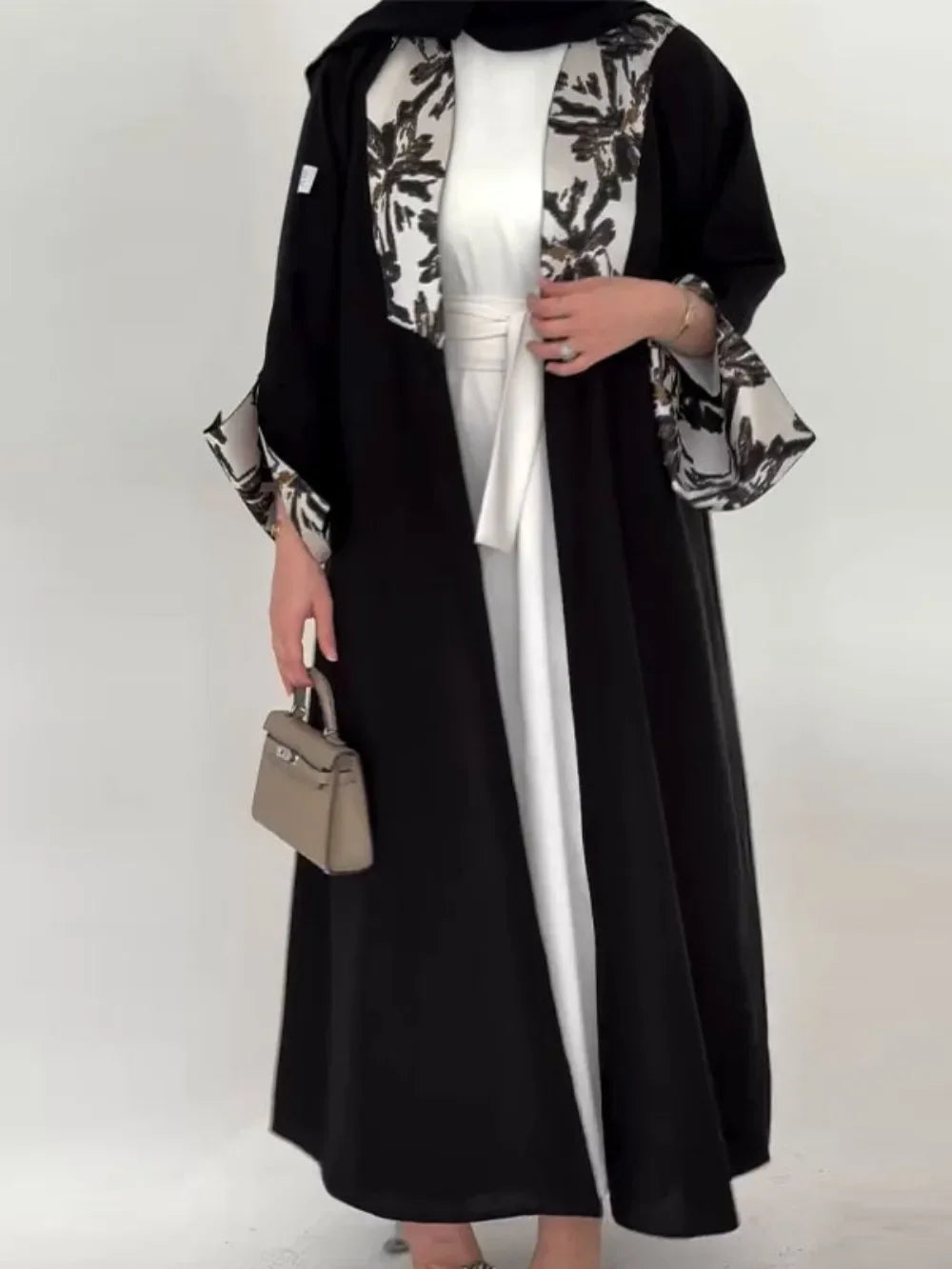Person wearing a black abaya with floral patterns on a white background