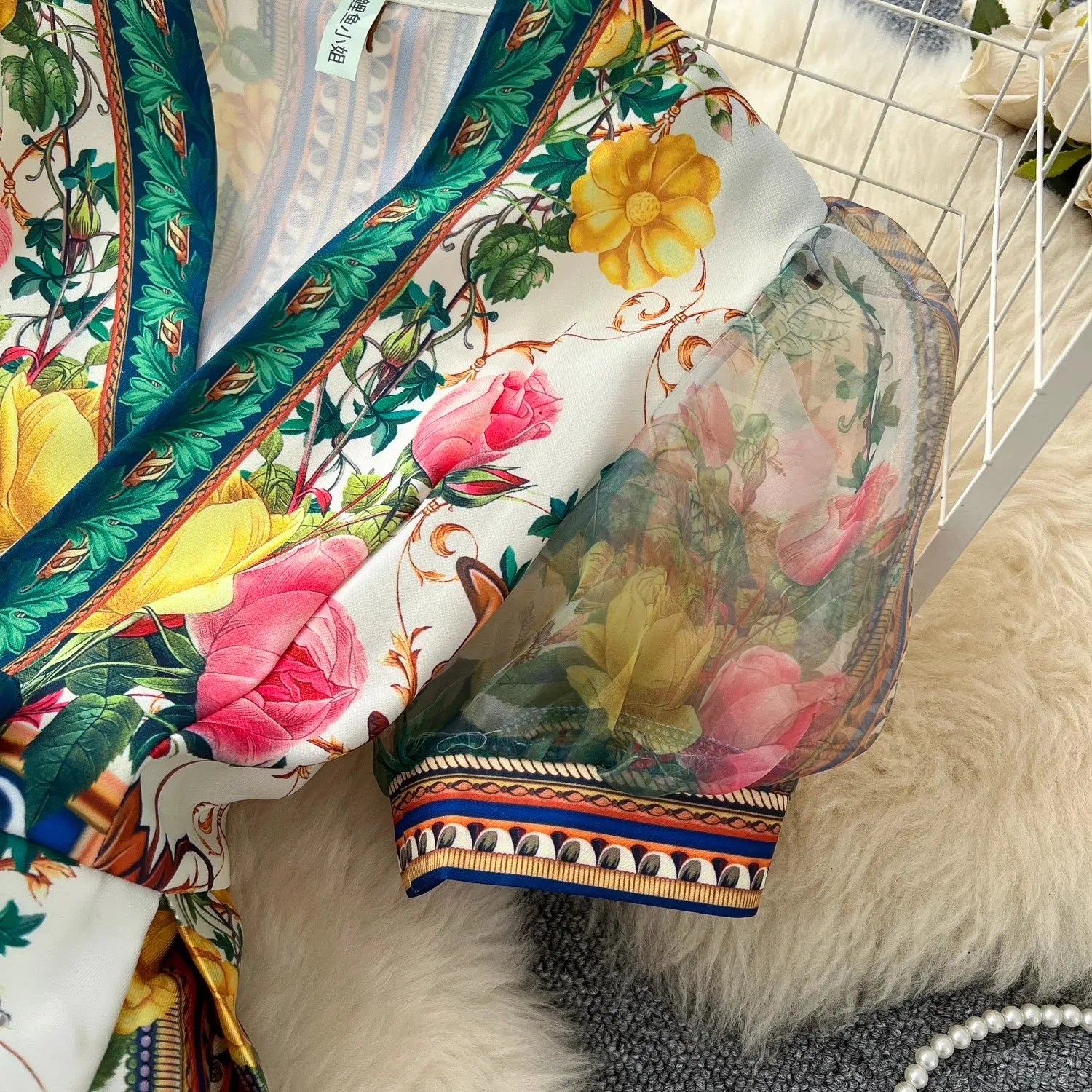 Colorful floral scarf with decorative border on a textured surface