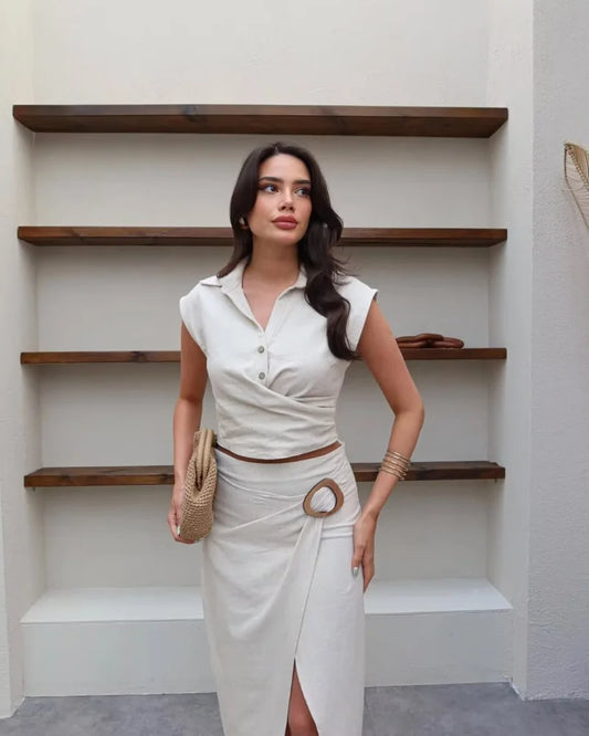 Woman in a white outfit standing in front of wooden shelves.