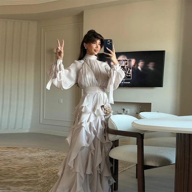 Woman in a white dress taking a mirror selfie in a modern room.