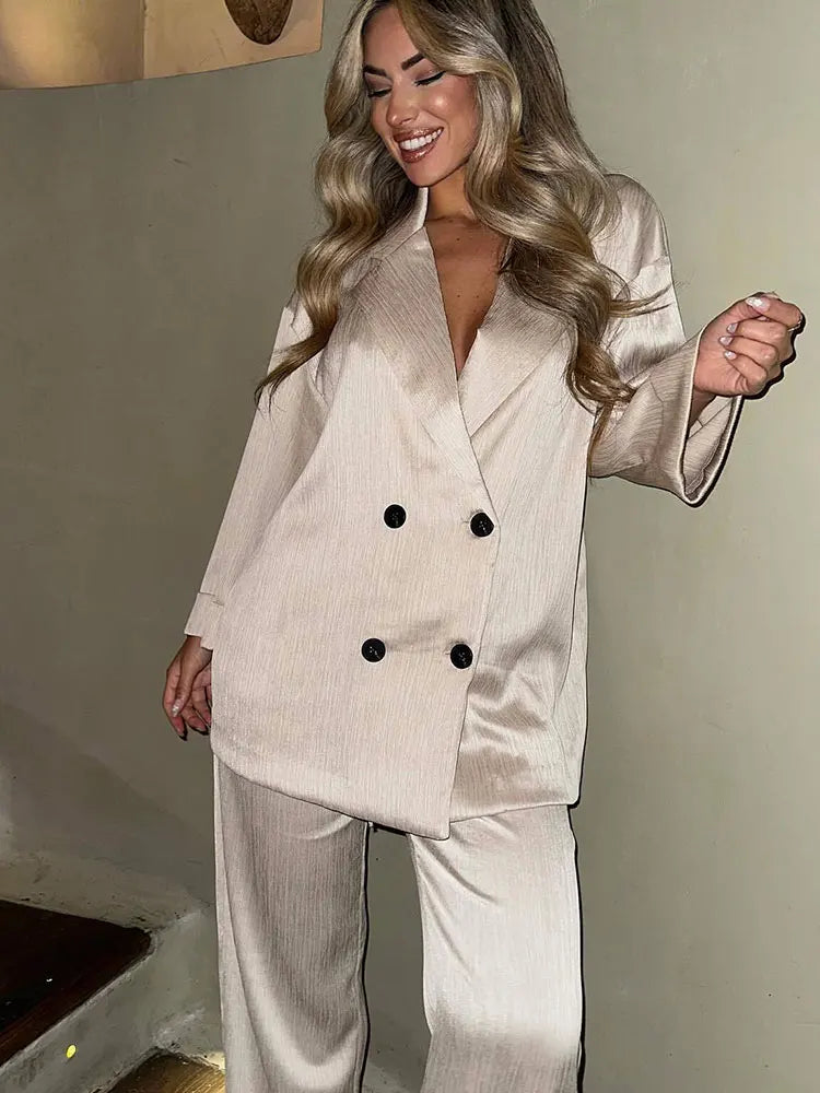 Woman wearing a beige suit with black buttons indoors.