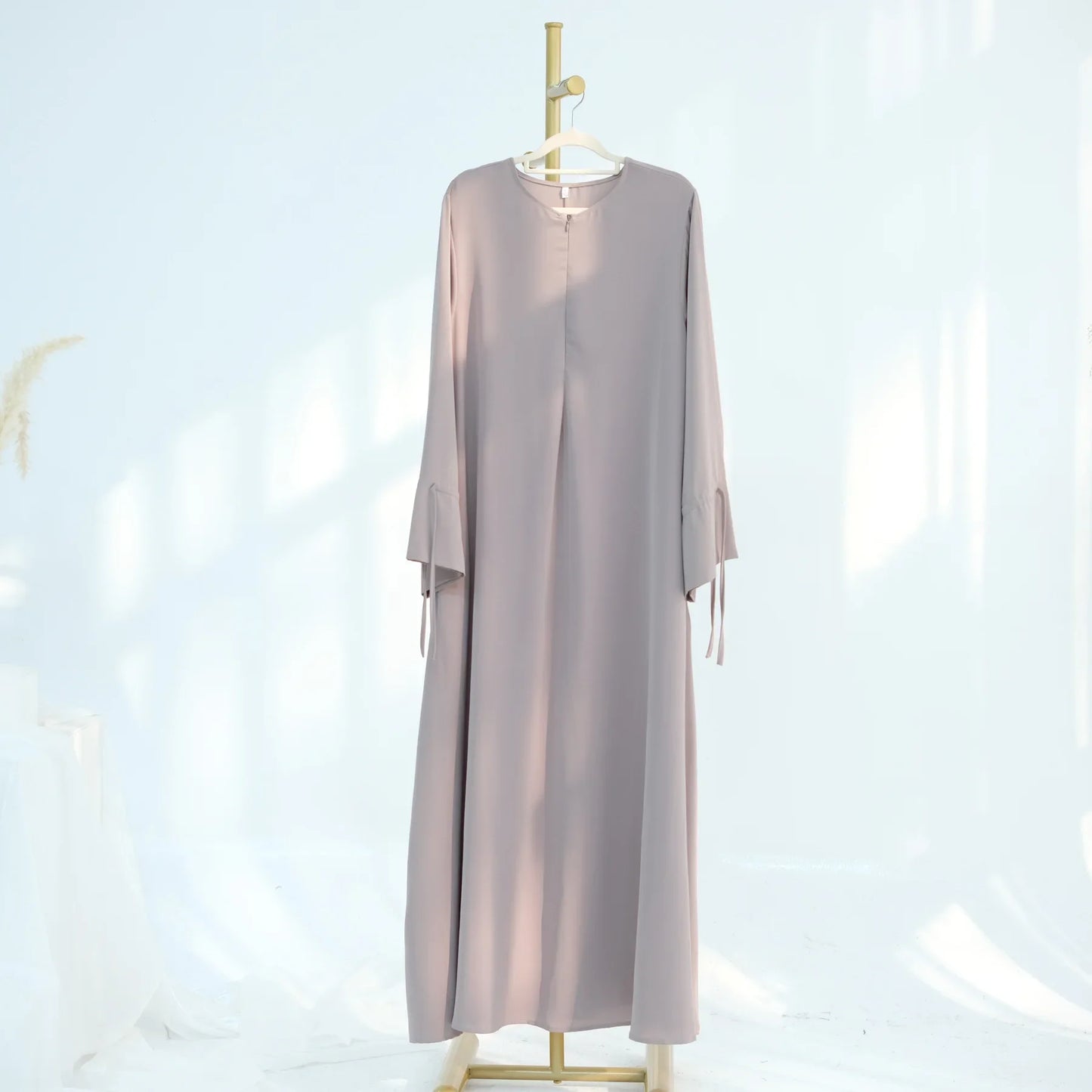 Light gray dress on a hanger against a light blue background