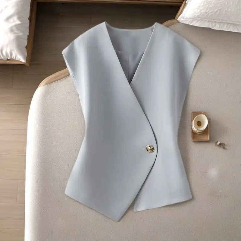 Light blue vest on a beige surface with a wooden block and small container.