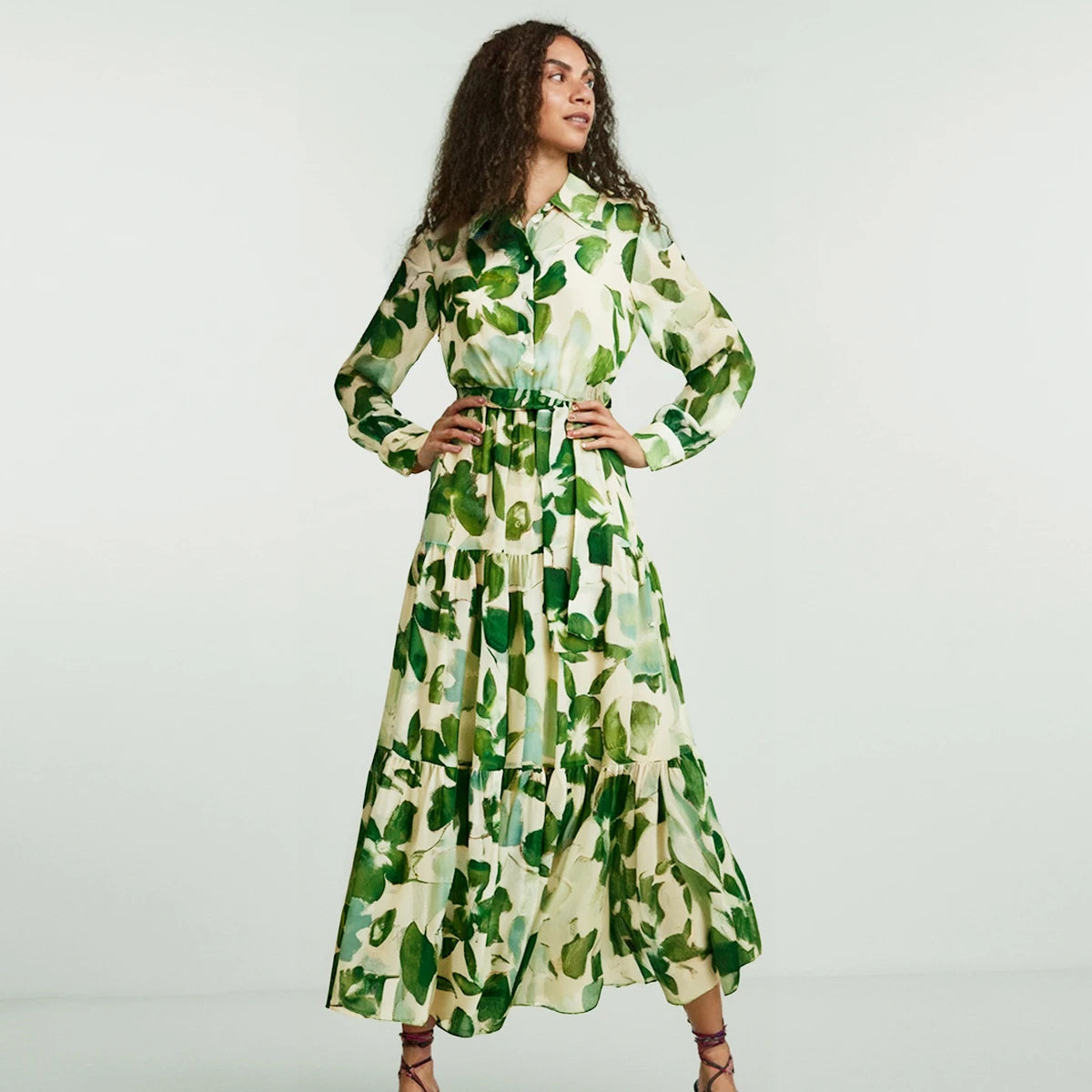 Woman wearing a green and white floral dress against a plain background
