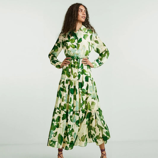 Woman wearing a green and white floral dress against a plain background