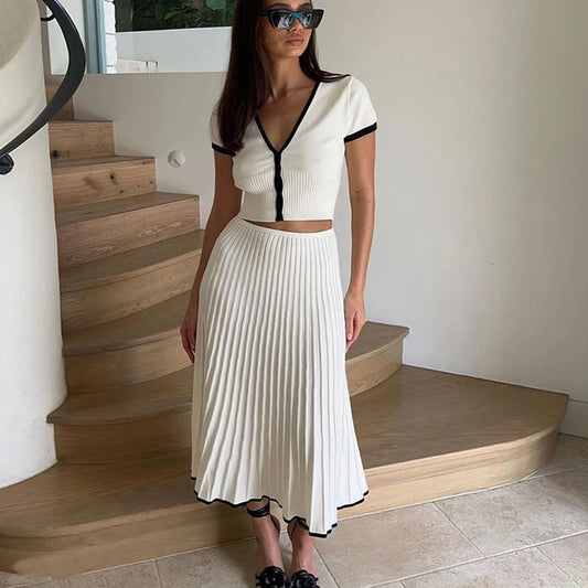 Woman in a white outfit with black trim standing on a staircase.