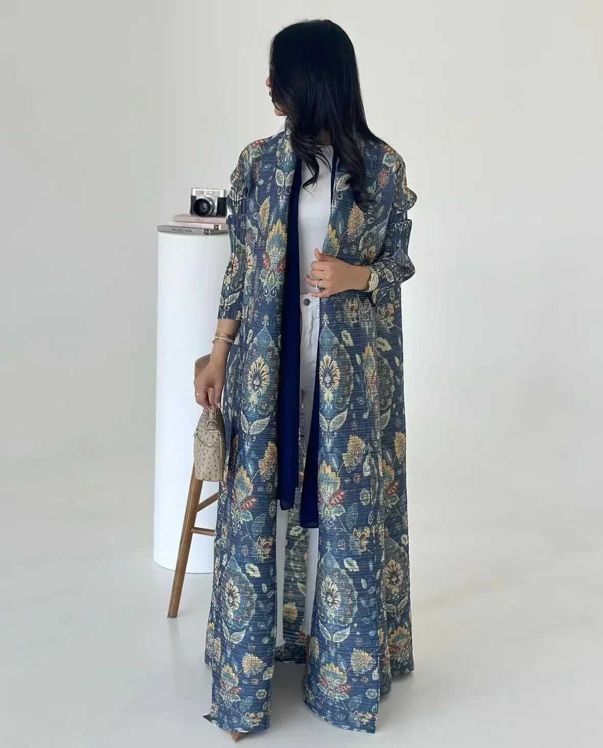 Woman wearing a long blue floral dress with a white background