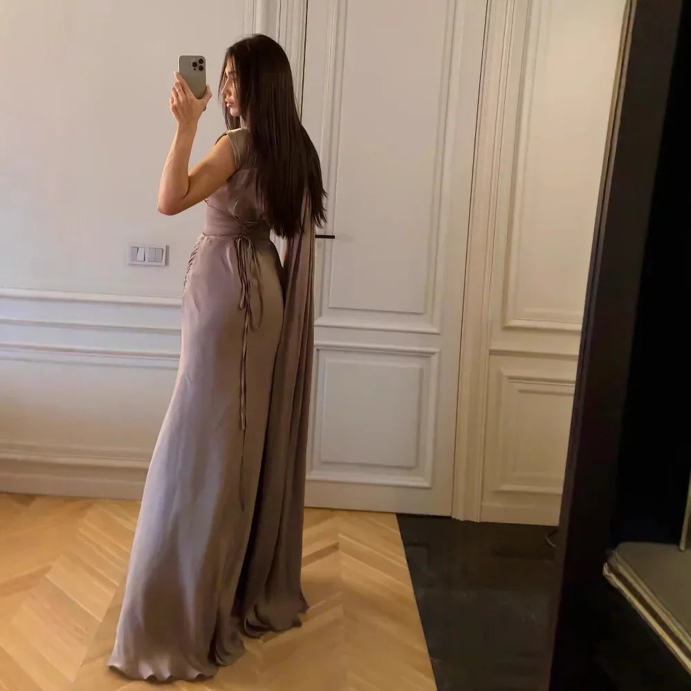 Woman in a long, light-colored dress taking a mirror selfie in an elegant room.