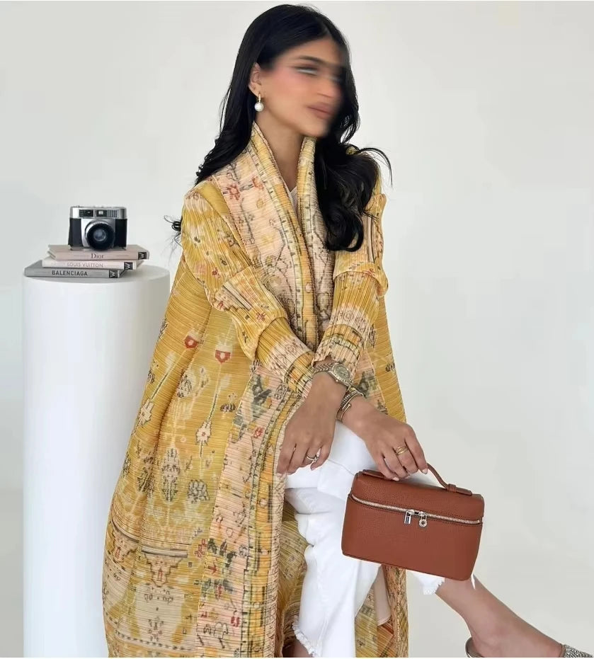 Woman wearing a yellow patterned shawl holding a brown handbag against a white background