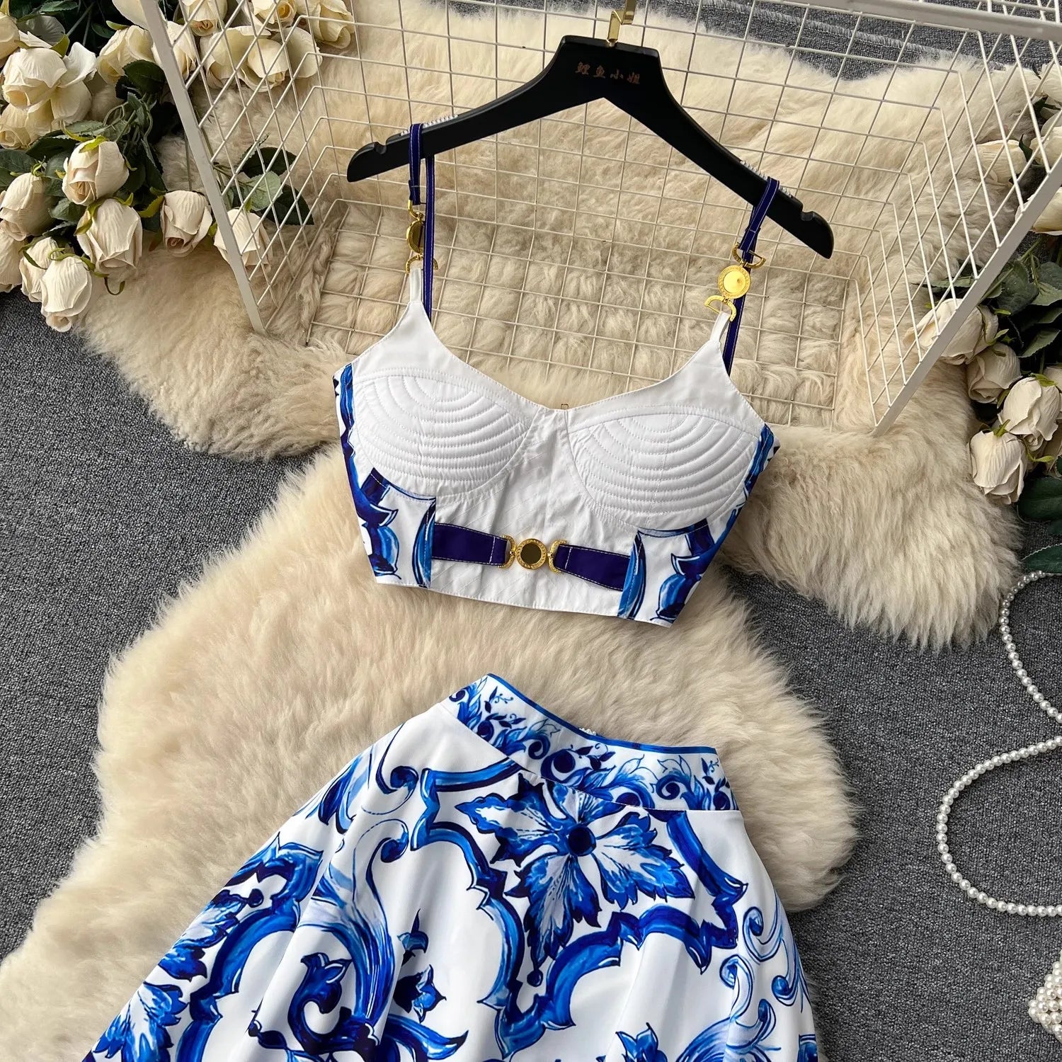 White bikini top with blue floral patterns on a hanger against a textured white background.