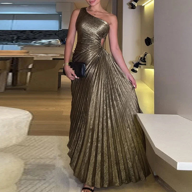 Woman in a gold one-shoulder dress holding a clutch in an indoor setting.