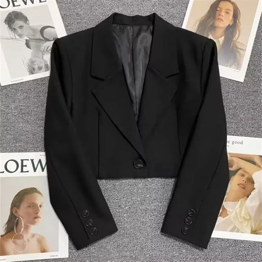 Black blazer on a textured surface with magazine clippings in the background