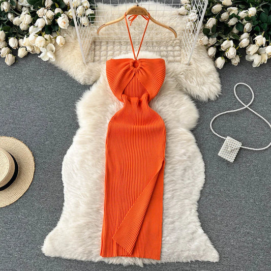 Orange halter top dress on a hanger with decorative elements on a gray surface