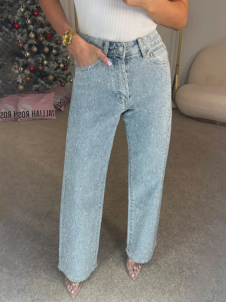 Person wearing light blue jeans in a room with a Christmas tree and beige sofa.
