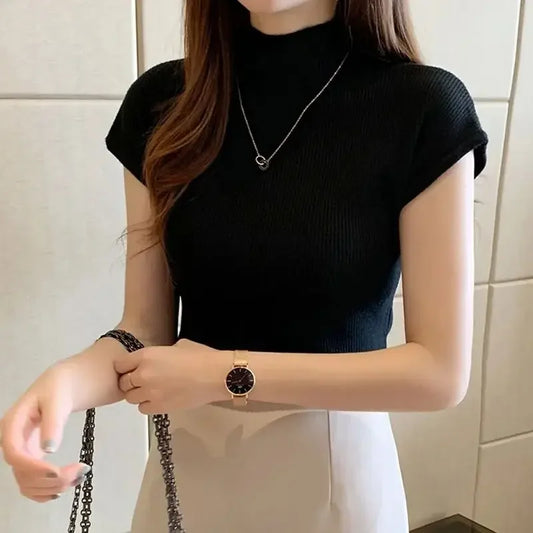 Person wearing a black top and a watch, standing against a tiled wall.