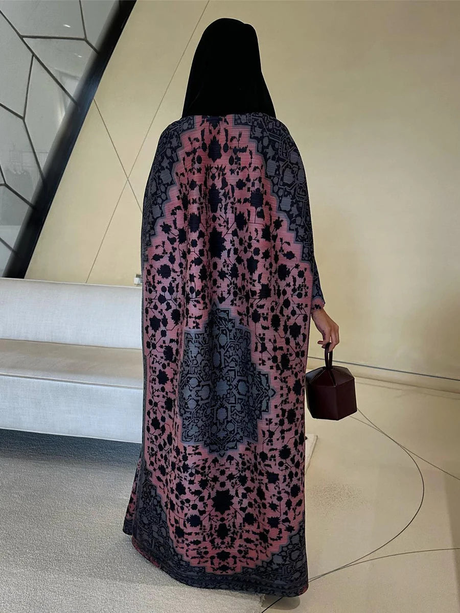 Person wearing a patterned dress with a hood, holding a handbag indoors.