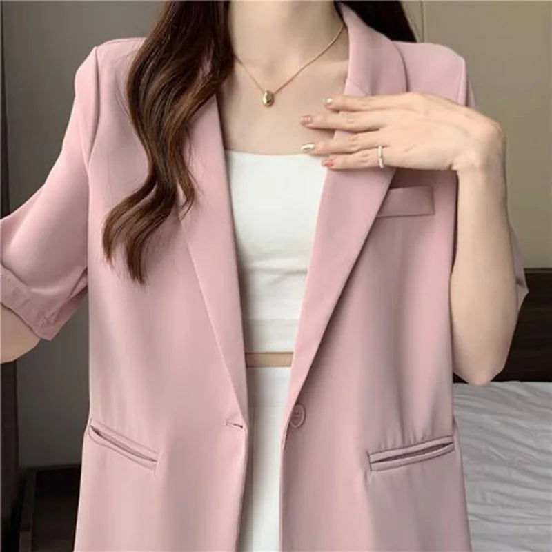 Person wearing a pink blazer over a white top with a neutral background