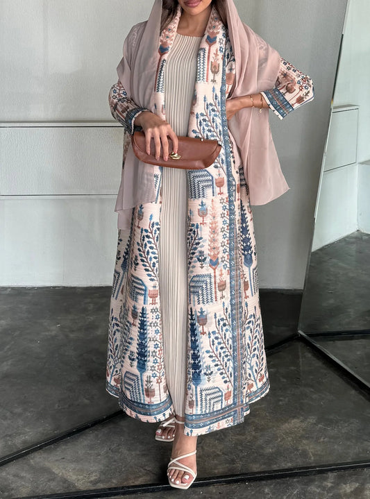 Woman wearing a long, patterned dress with a matching hijab in an indoor setting.